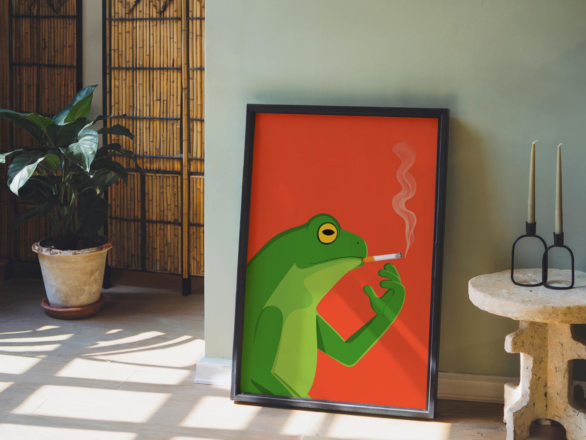 Funny frog wall art print propped on floor beside potted plant, quirky smoking frog poster