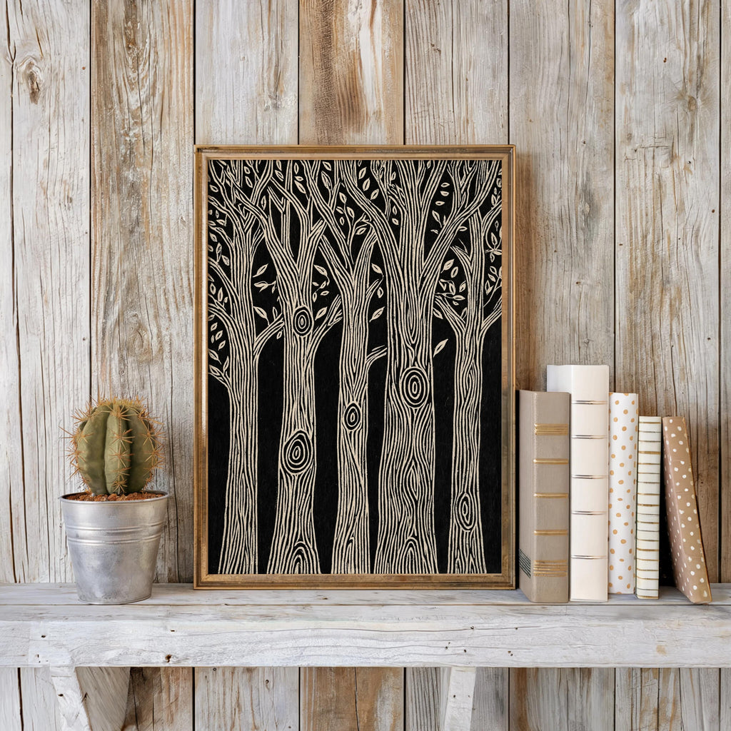 Black and white forest wall art framed against weathered wood, stacked books and a small cactus, woodcut tree print styling