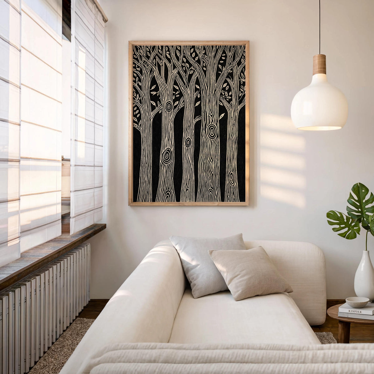 Vertical black and white forest wall art hung above a neutral sofa with a pendant lamp, modern rustic wall art, linocut forest print