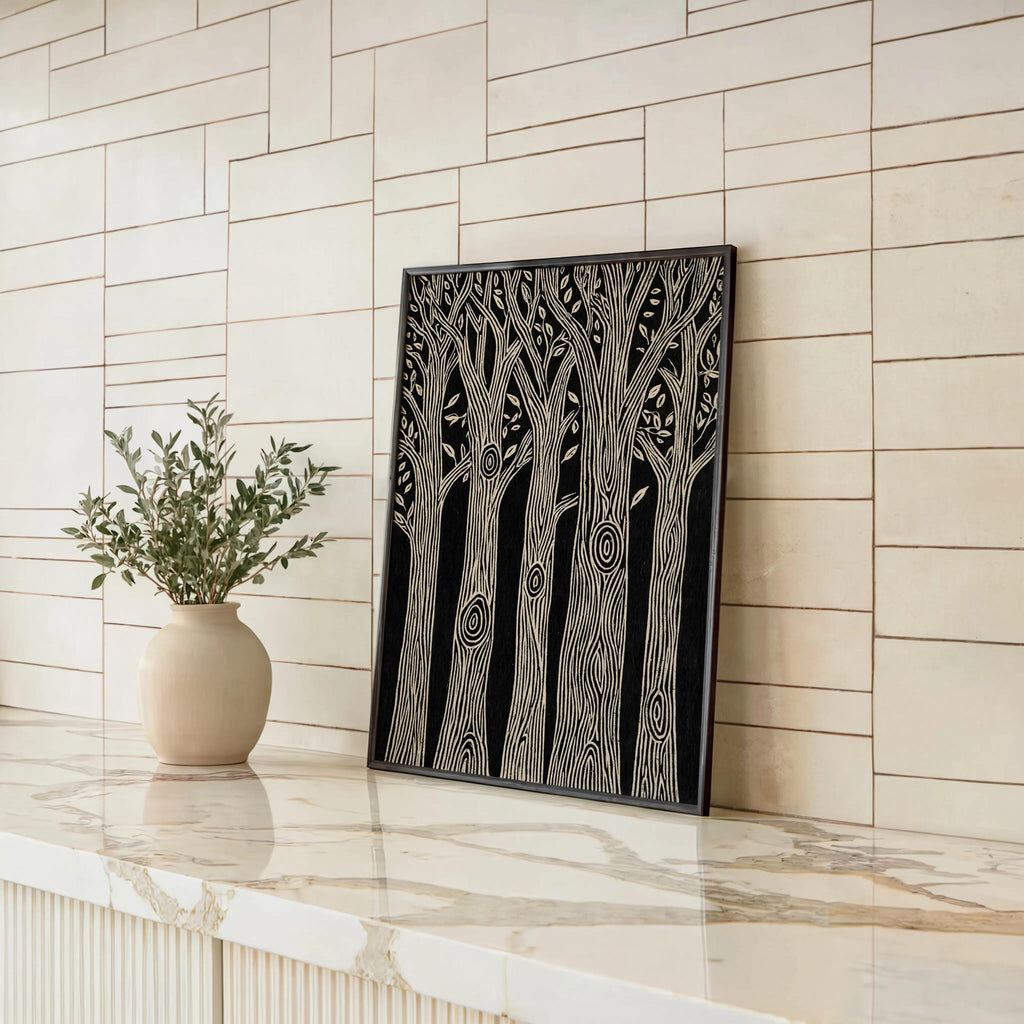 Black and white forest wall art leaning on a bright shiplap counter, ceramic vase nearby, minimalist botanical tree print display