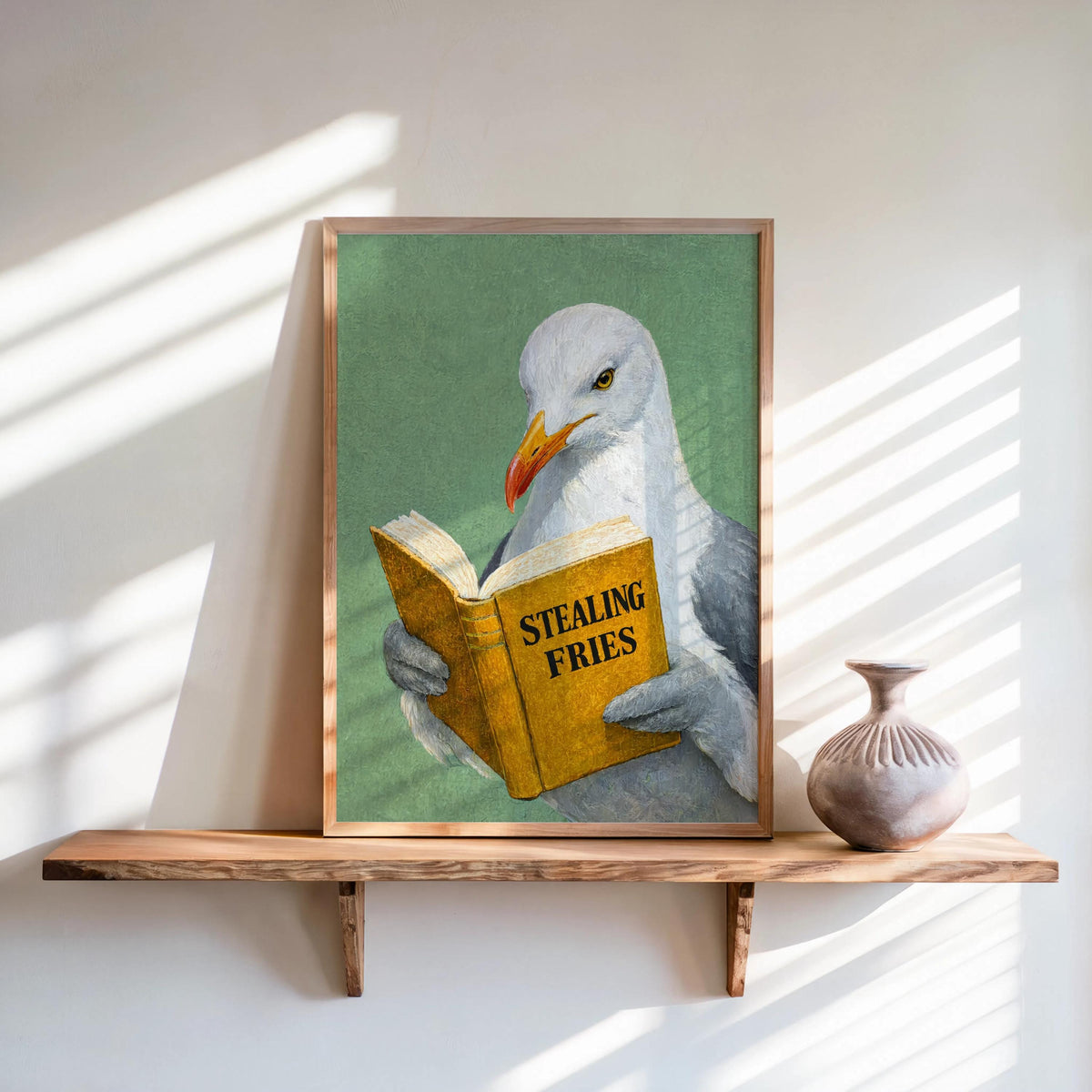 Green backdrop framed print, seagull clutching yellow book on wooden shelf, funny seagull reading art print
