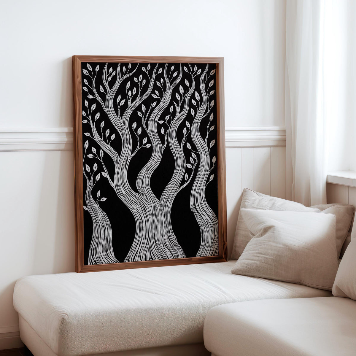 Moody black background tree art in a natural wood frame leaning against neutral sofa, monochrome woodland print