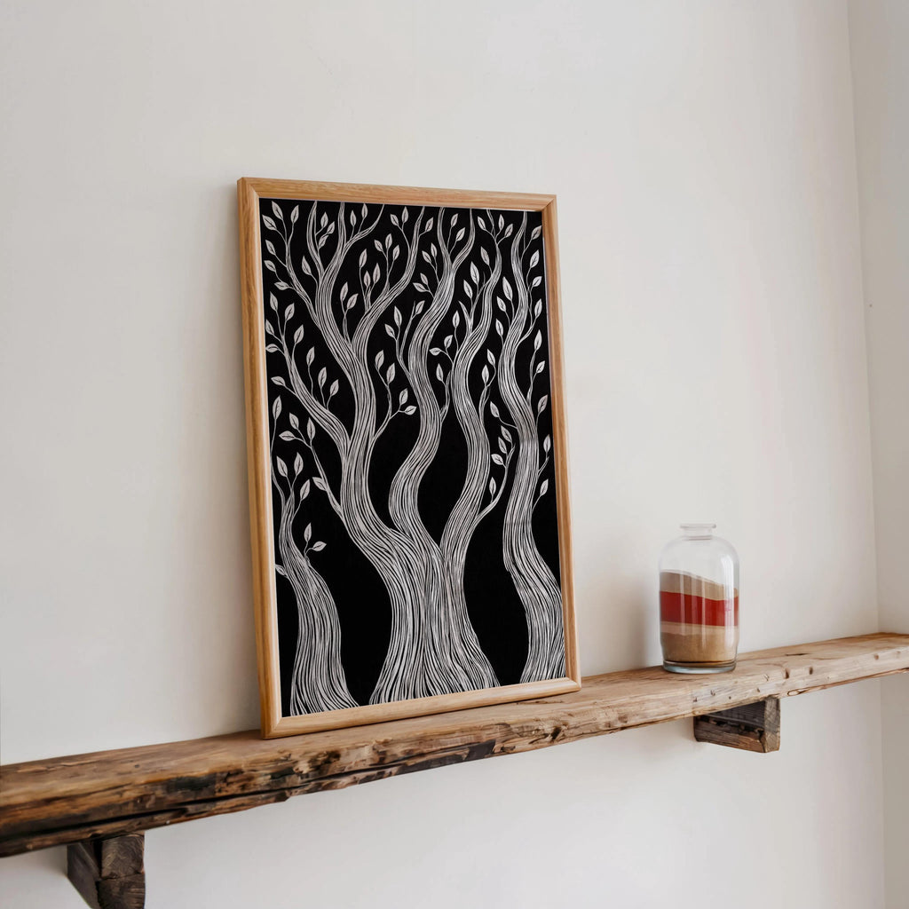 Leaning framed black background tree art on reclaimed wood shelf, twisted tree wall art next to glass candle jar