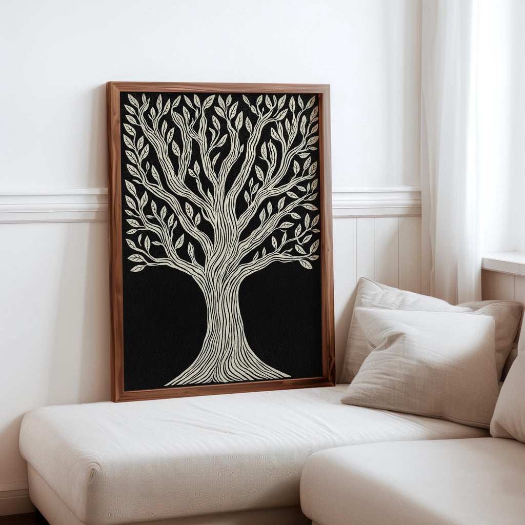 Tree of Life wall art leaning on a white chaise, warm wood frame, high-contrast black and cream linocut print.