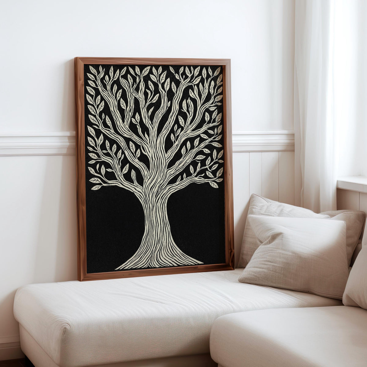 Tree of Life wall art leaning on a white chaise, warm wood frame, high-contrast black and cream linocut print.
