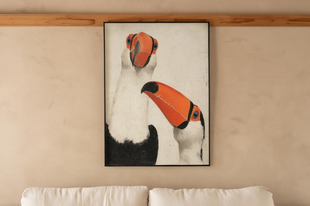 Framed toucan wall art print displayed above sofa rail, cozy neutral living room, modern tropical wall art