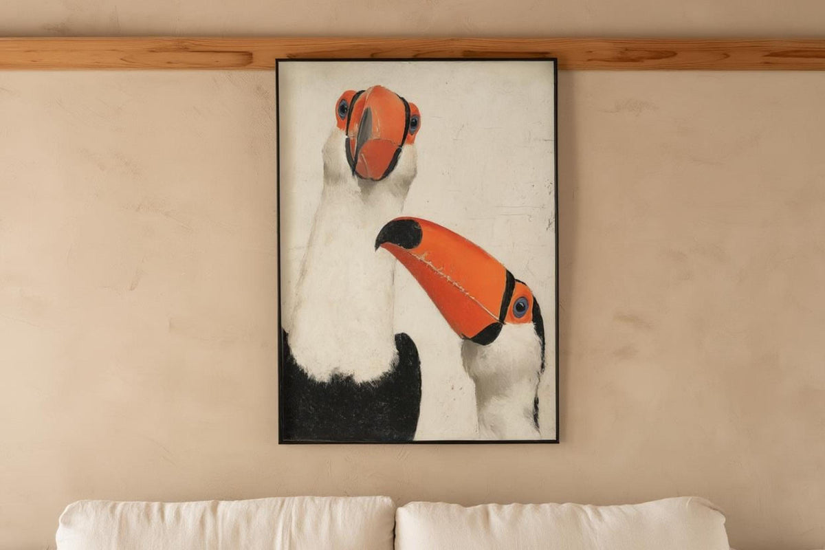 Framed toucan wall art print displayed above sofa rail, cozy neutral living room, modern tropical wall art
