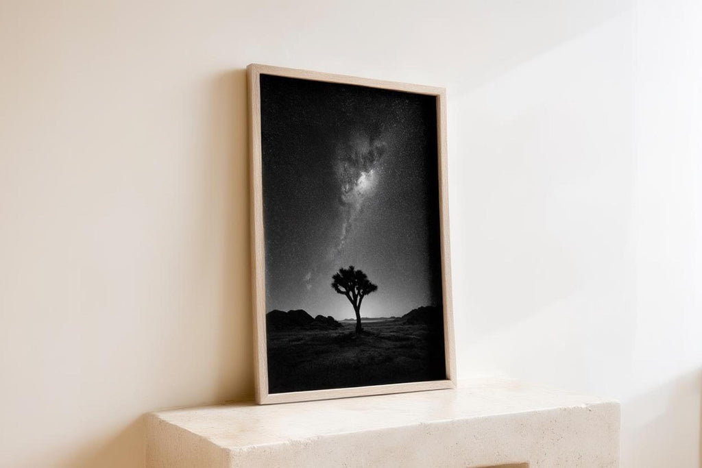 Angled wooden frame leaning on a ledge, black and white desert night sky wall art catching soft daylight