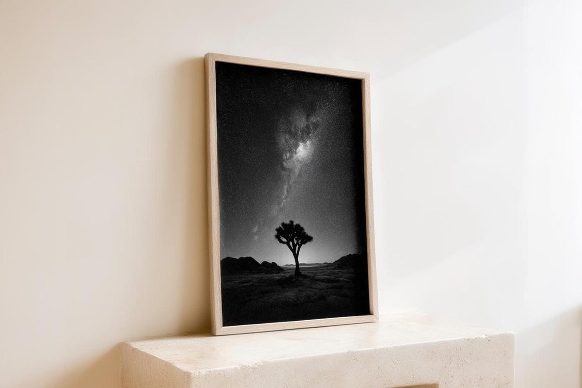 Angled wooden frame leaning on a ledge, black and white desert night sky wall art catching soft daylight