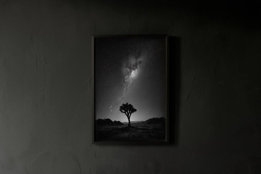 Low-light interior showing a starry sky landscape print in a matte frame on a textured dark wall