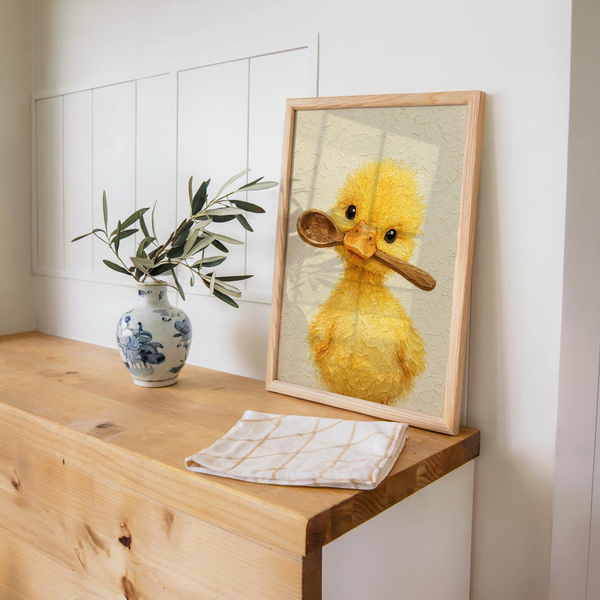 Wood console styling with folded linen and vase, cottagecore animal art featuring a smiley yellow duck kitchen art print.