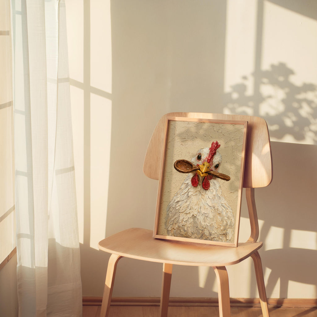 Mini framed funny chicken art print rests on a wooden chair, soft morning light, chicken kitchen wall art