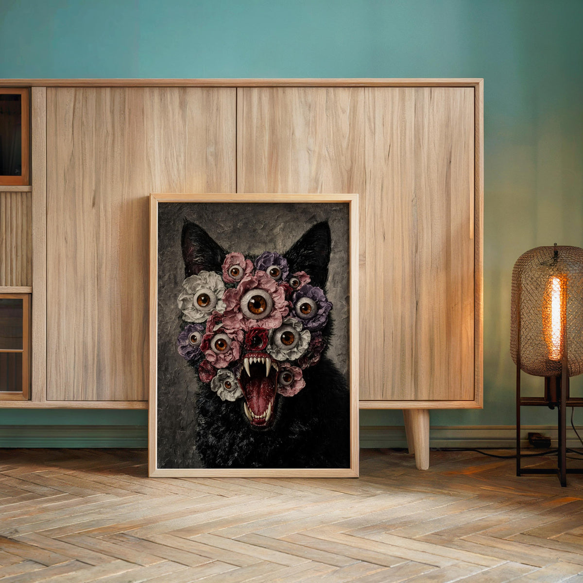 Creepy black cat poster framed against a teal wall above a low cabinet, black cat floral wall art in warm lamp glow