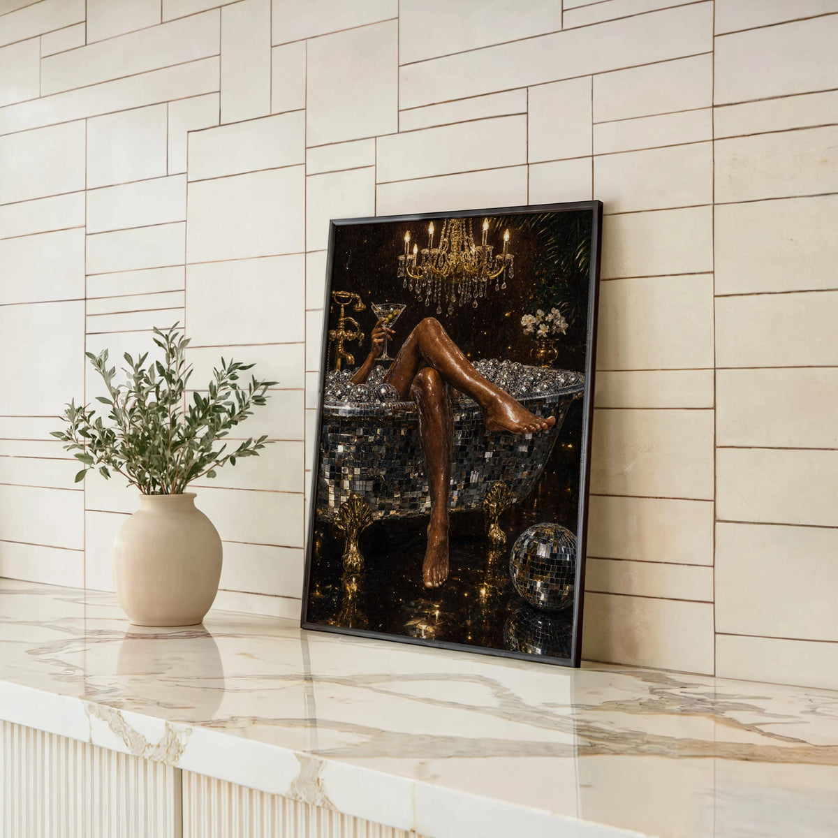 Disco ball bathtub art print leaning on a marble countertop against white tile, black and gold wall art, small plant accent