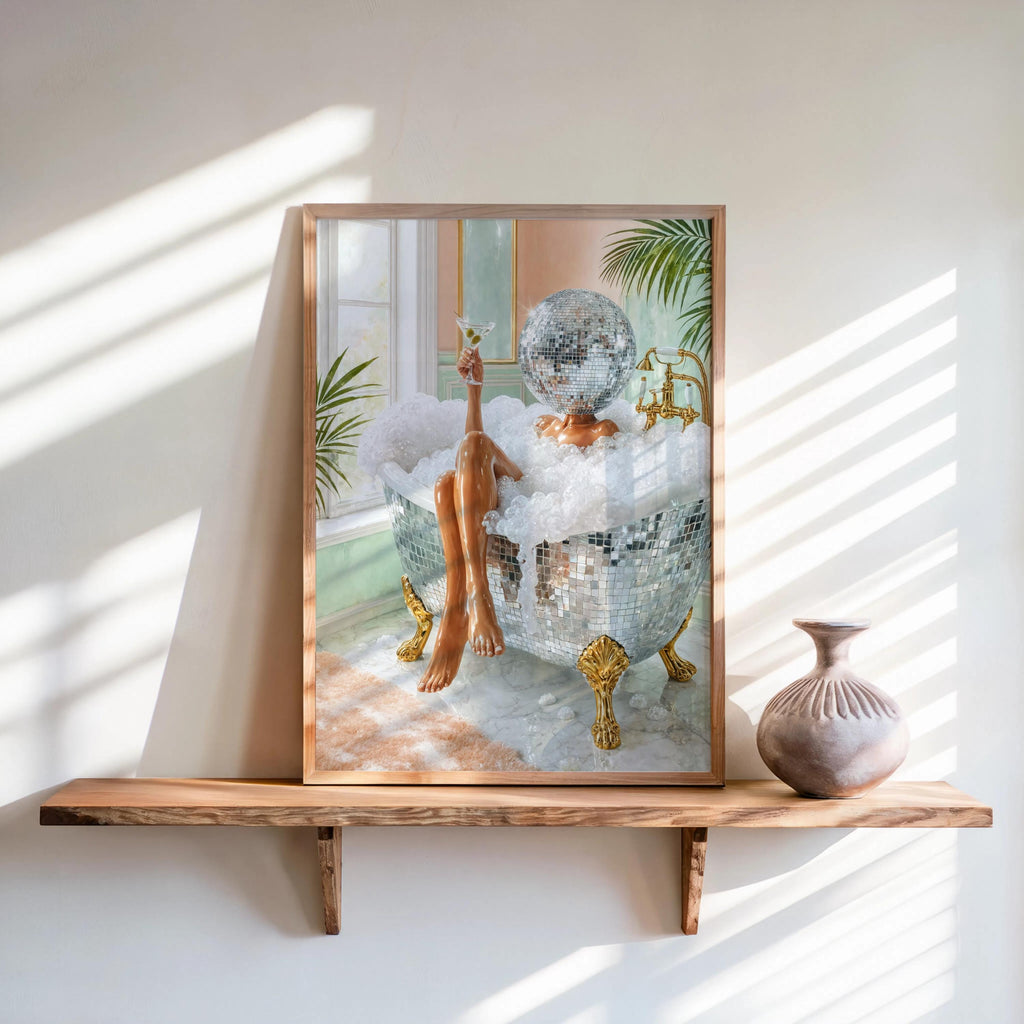 Framed disco ball bathroom art print leaning on sunlit wooden shelf, delicate vase and brass faucet accents