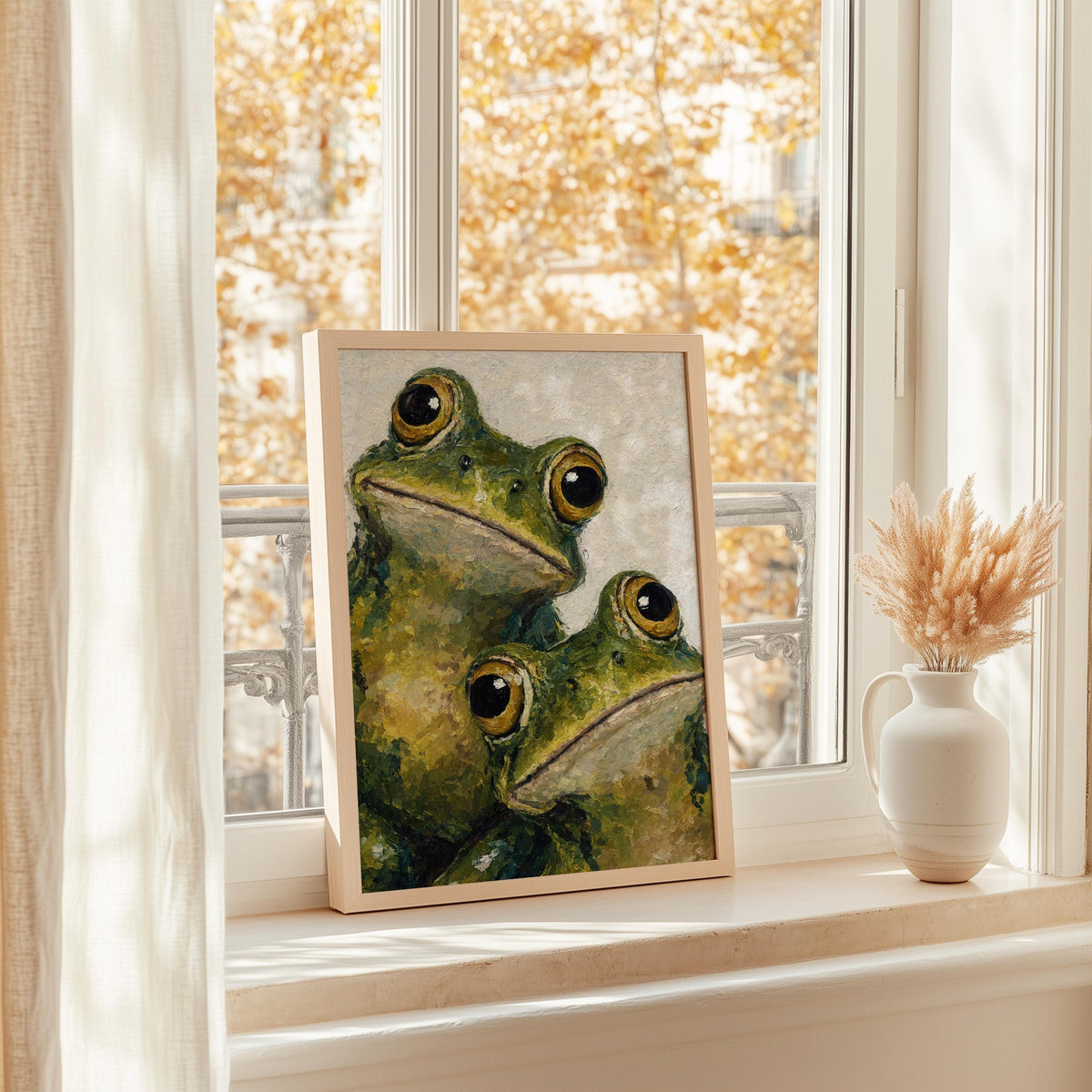 Cute frog art print on a sunlit windowsill, autumn light, vase of dried grasses, cozy cottagecore vibe.