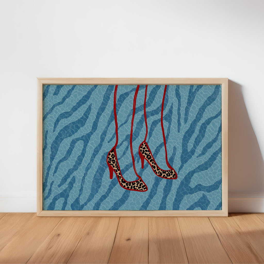 Framed print leaning on wood floor, blue zebra backdrop, hanging leopard stiletto heels, leopard heels wall art