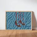 Framed print leaning on wood floor, blue zebra backdrop, hanging leopard stiletto heels, leopard heels wall art
