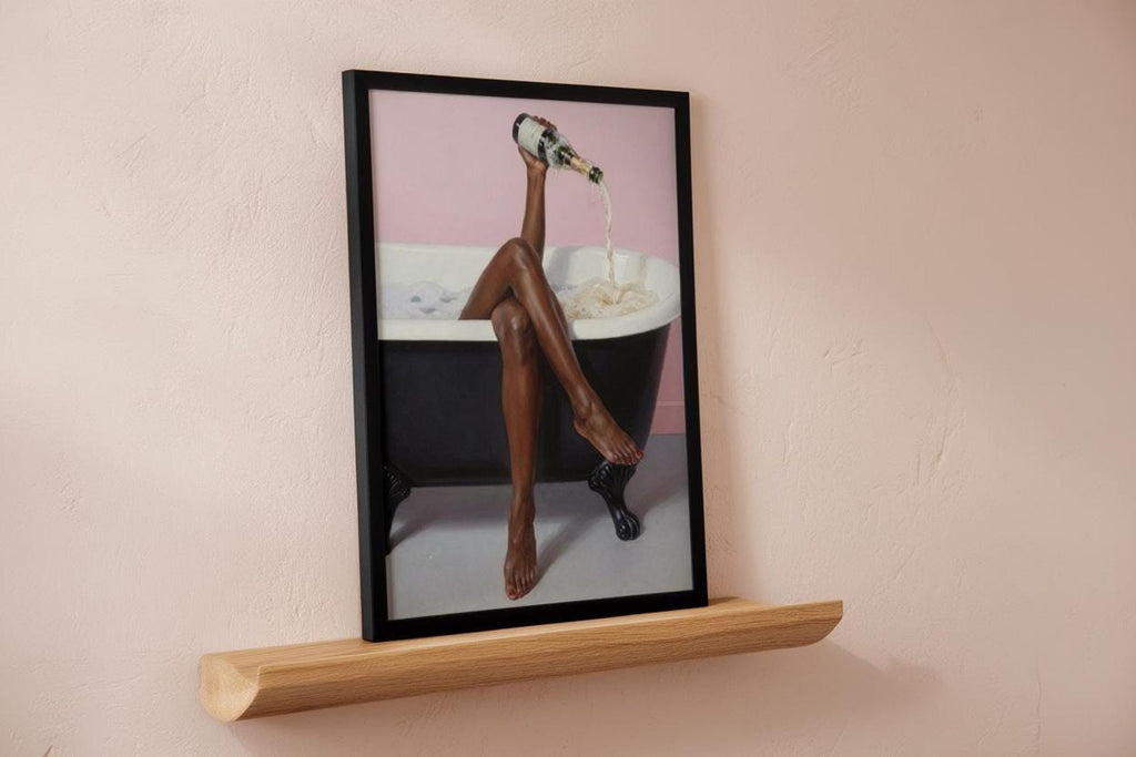 Framed print on a low wooden shelf against a blush wall, pink bathroom wall art styling, black woman bathroom wall art
