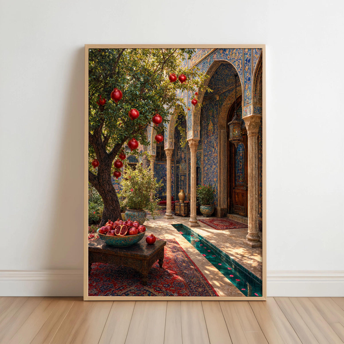 Framed Persian courtyard wall art leaning on a white wall, sunlit arches, pomegranate tree, blue-green tiled pool