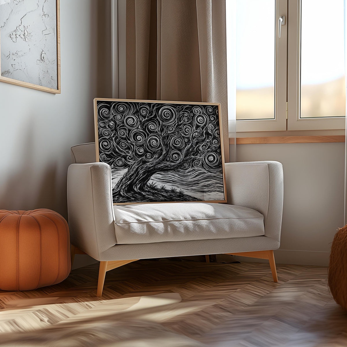 Framed black and white tree linocut print propped on an upholstered armchair by a window, cozy neutral black and white wall decor