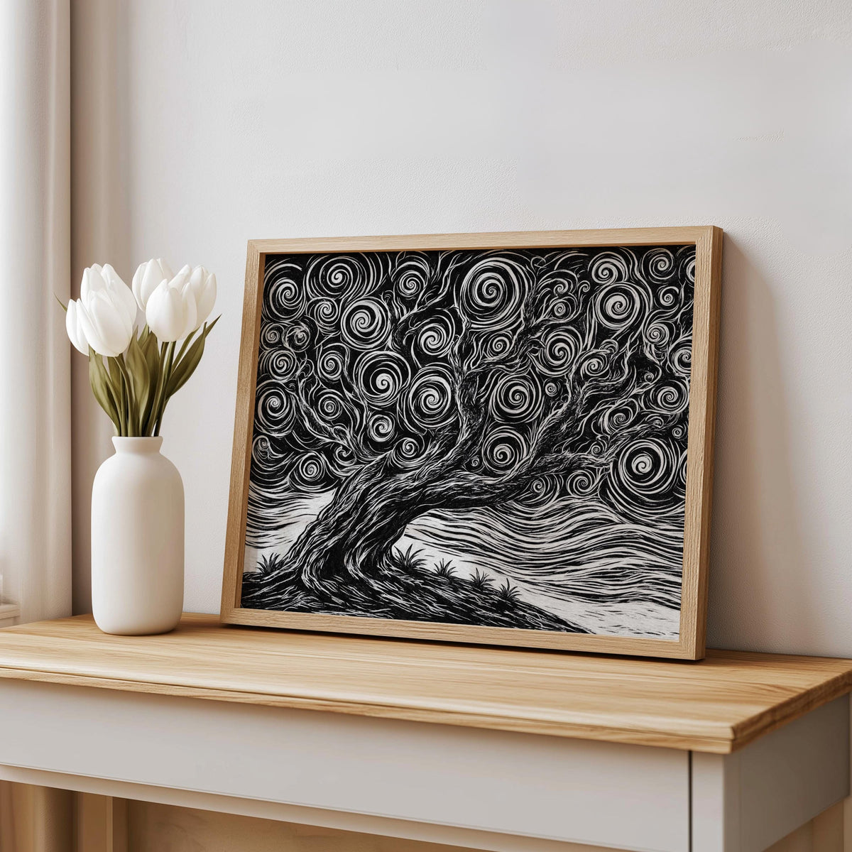 Black and white tree linocut print in wood frame displayed on a console beside white tulips, ukiyo-e inspired stormy tree art