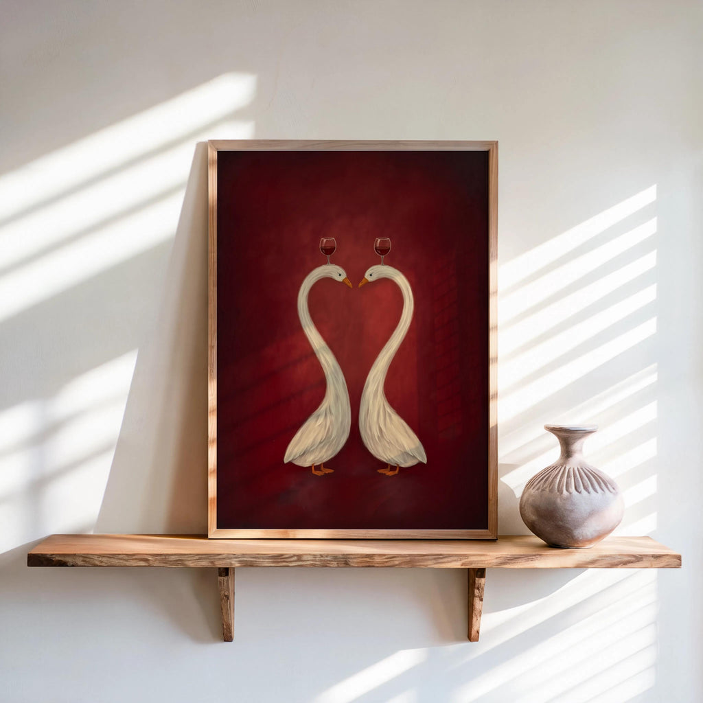 Framed burgundy heart swan print leaning on shelf, paired white swans with tiny red hearts, refined style