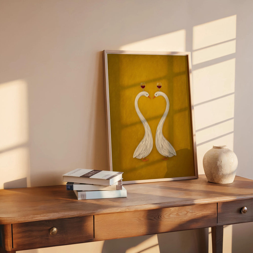 Mustard modern animal art print on table, framed swans forming a heart with books and vase, colorful minimalist wall art