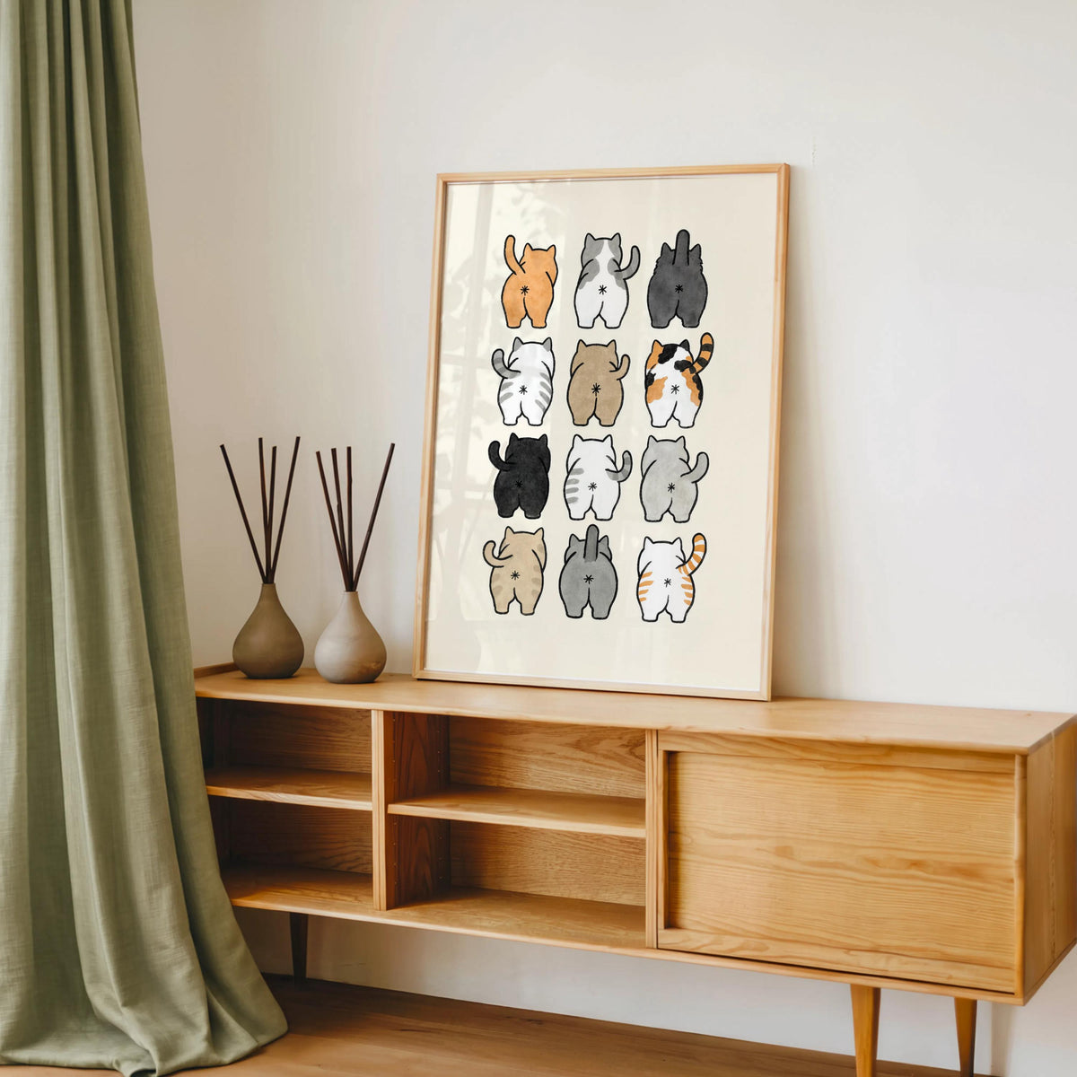 Print displayed above a mid-century credenza with draped green curtain, whimsical cat butt bathroom decor for kids or guests