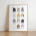 Framed print leaning on white wall, 3-by-4 grid of stylized dog backsides, minimalist dog butt bathroom wall art