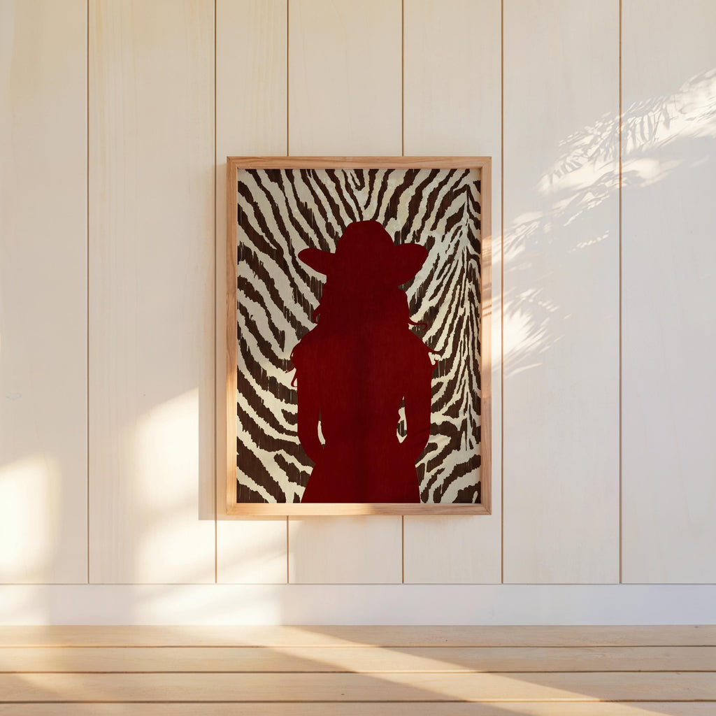 Modern western wall art hung on white panel wall, red cowgirl silhouette, high-contrast zebra background