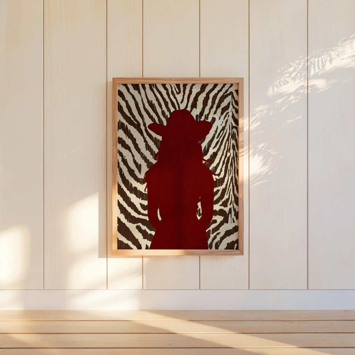 Modern western wall art hung on white panel wall, red cowgirl silhouette, high-contrast zebra background