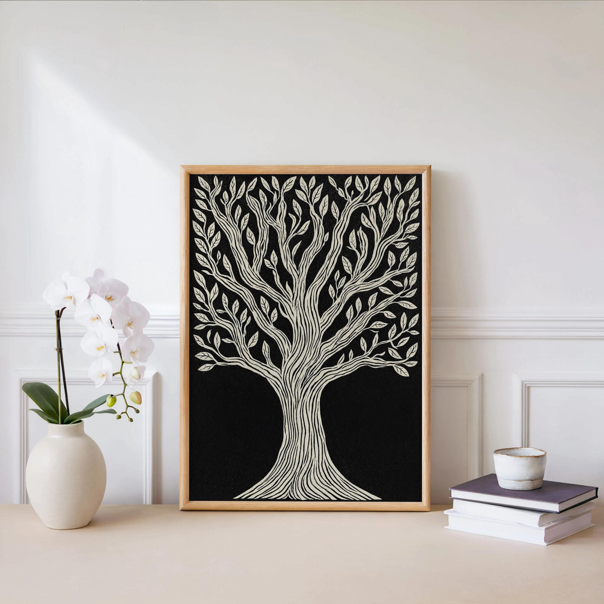 Tree of Life wall art leaned beside a white orchid and stacked books, minimalist botanical print with warm frame.