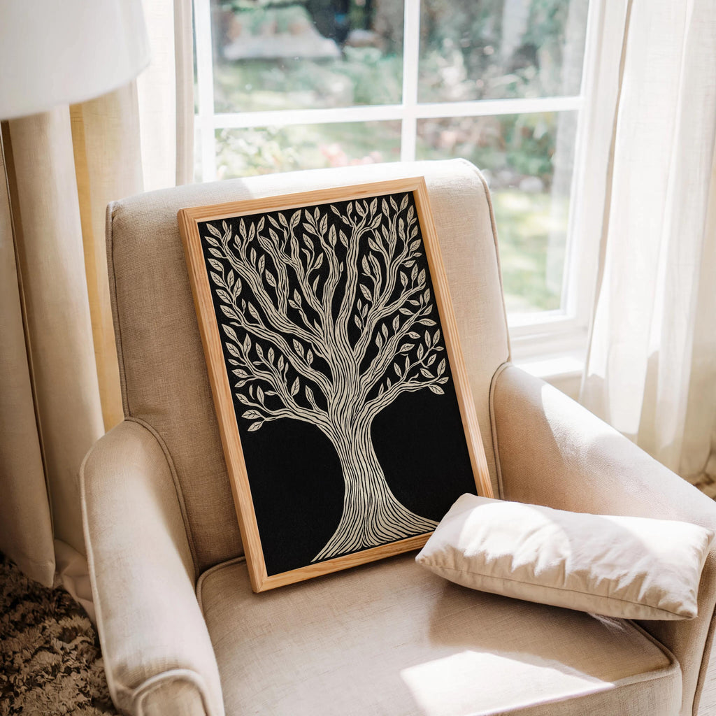 Tree of Life wall art framed and resting on cozy armchair by window, black and cream linocut, housewarming wall art gift.