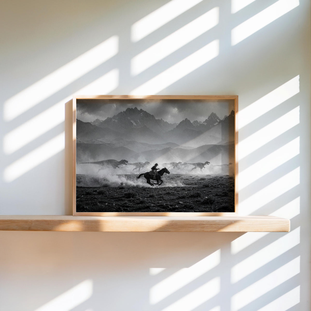Sunlit floating shelf holds framed cowboy dinosaur wall art, strong stripes of light across archival paper