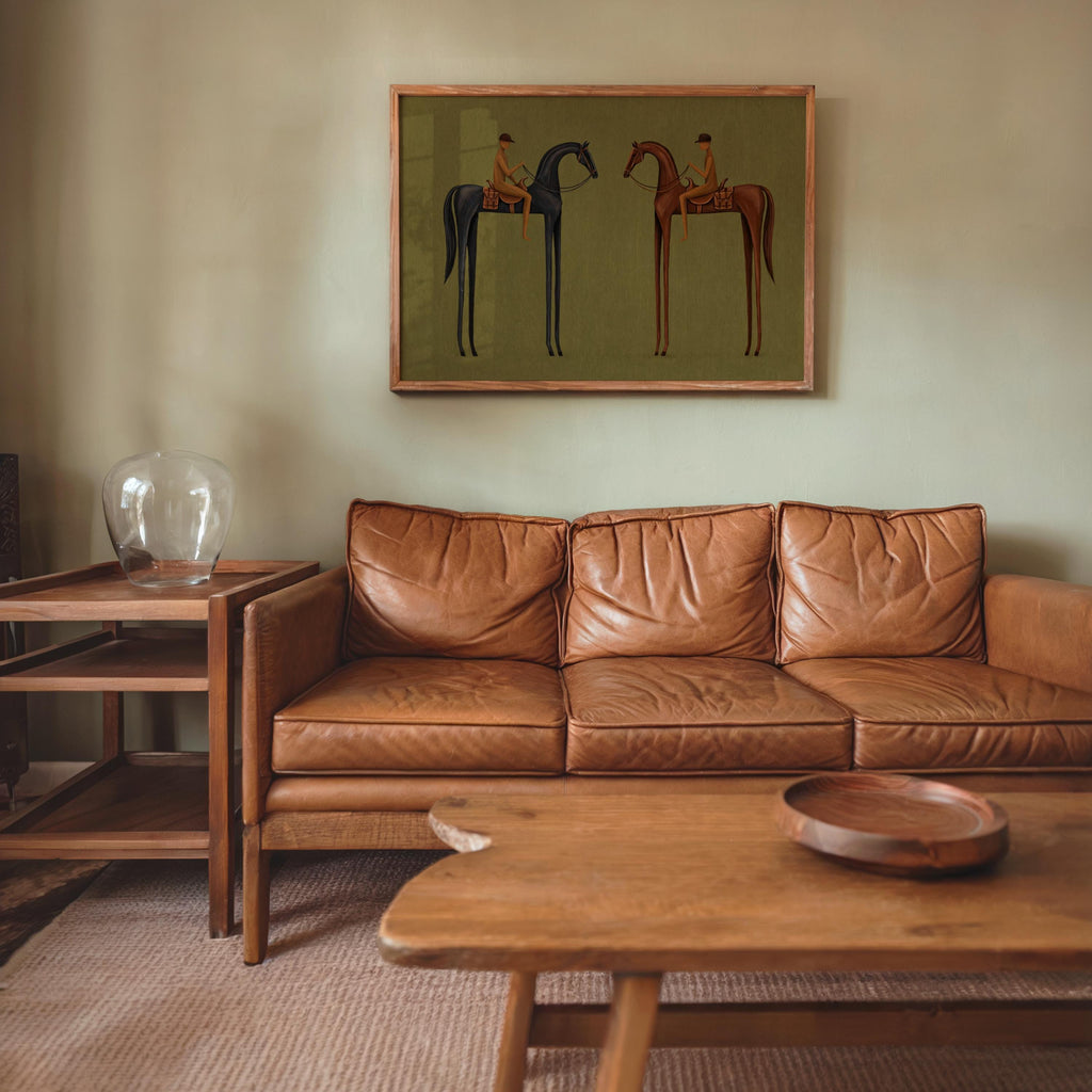 Modern horse wall decor above tan leather sofa, gallery style horizontal olive green equestrian print