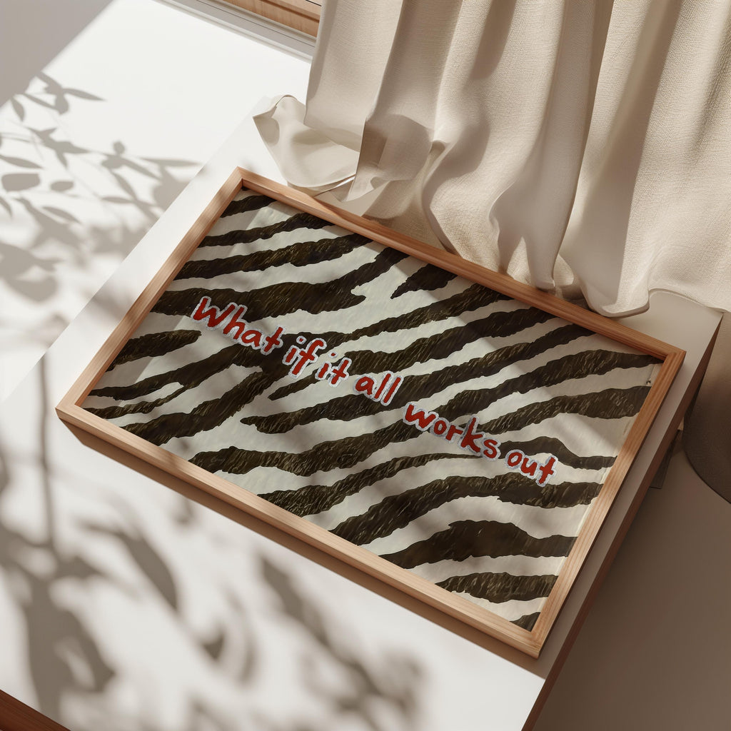 Close angled view of framed custom animal print wall art laid on fabric, brown and cream zebra stripes with red text