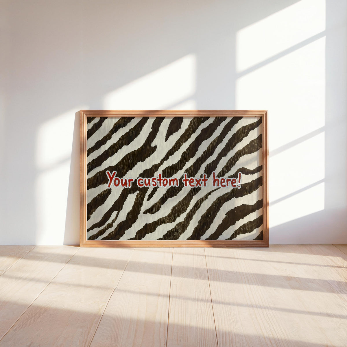 Framed personalized zebra print wall art leaning on a sunlit wooden shelf, bold red typography visible