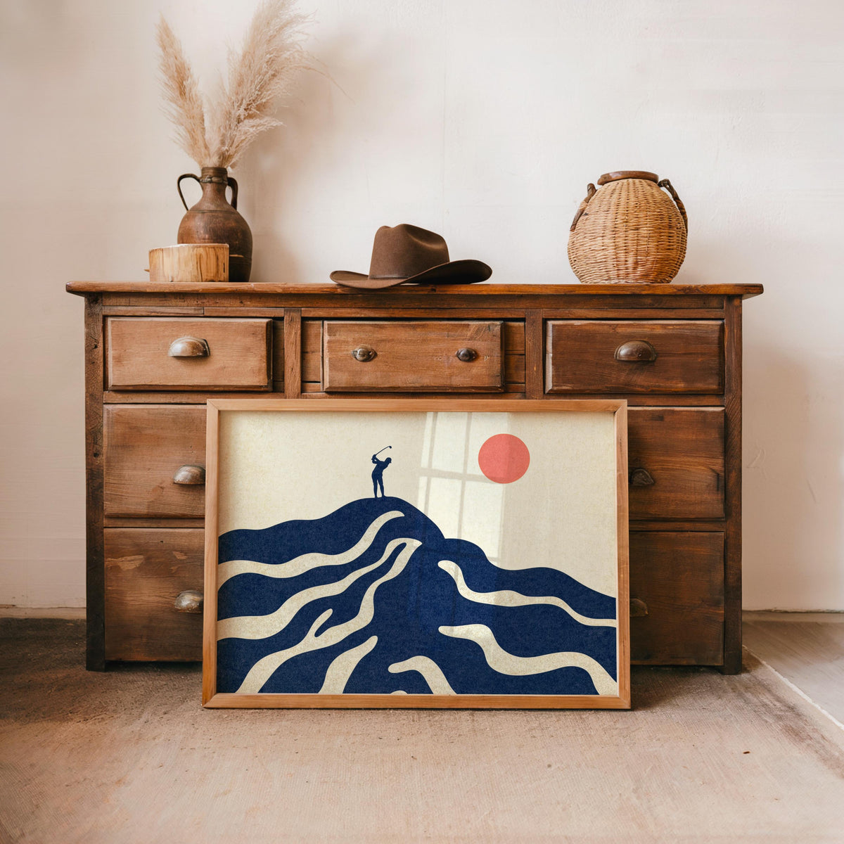 Navy mid century golf art print propped beneath a wooden dresser, blush sun, styled as golf wall art