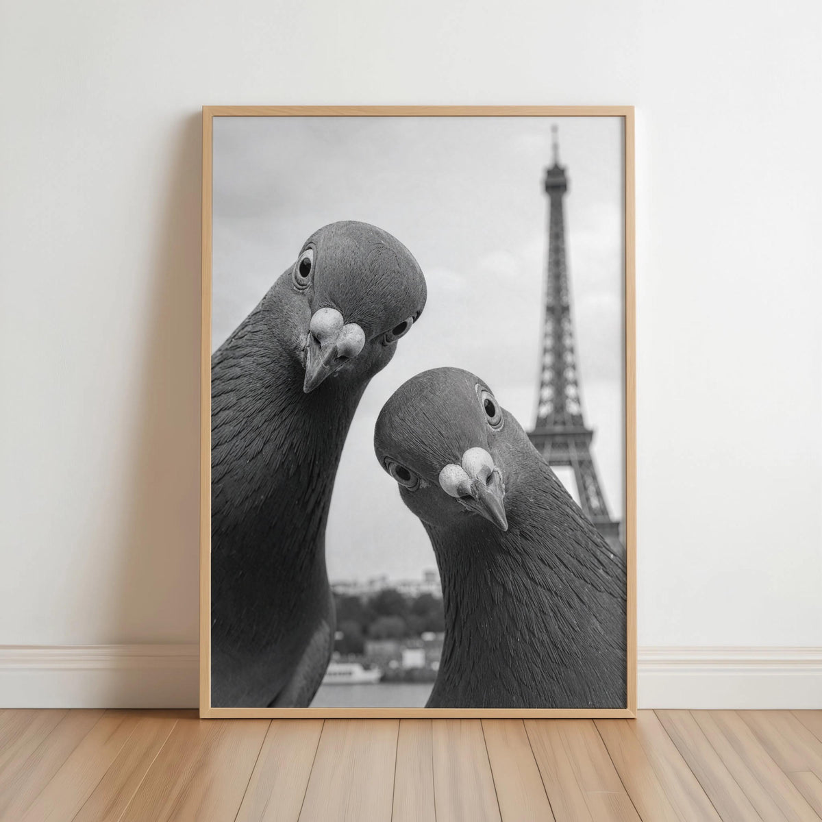 Black and white portrait print in a light wood frame leaning on floor, pigeons with Eiffel Tower, funny pigeon wall art