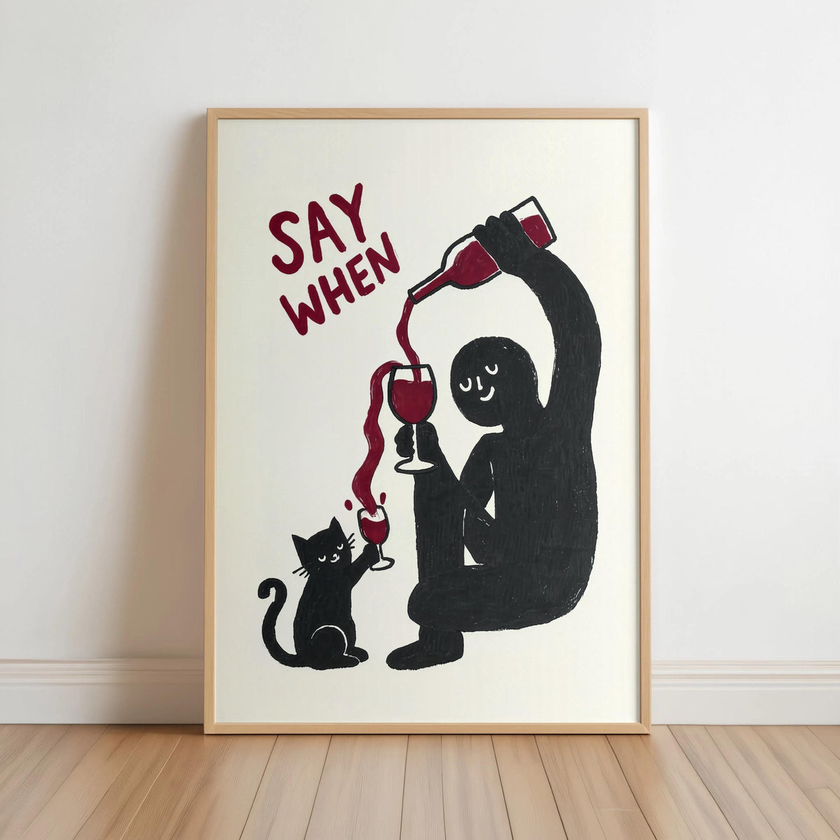 Framed black SAY WHEN print on floor, bold burgundy wine pour visible, cat wine print, funny cat wine wall art