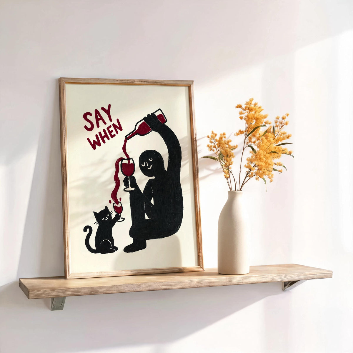 Black SAY WHEN print on shelf with dried stems, soft sunlight, cat lover gift vibe, funny cat wine wall art