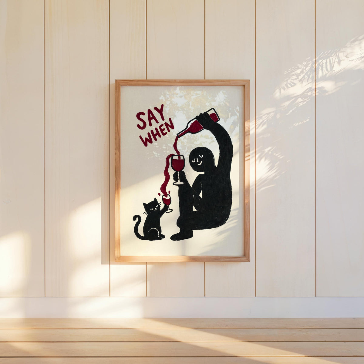 Wall-mounted navy SAY WHEN poster on white paneled wall, sunlit shadows, quirky dining room decor, funny cat wine wall art