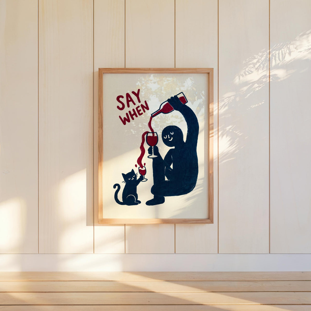 Framed navy SAY WHEN poster on paneled wall, angled sunlight and warm tones, home bar wall art, funny cat wine wall art