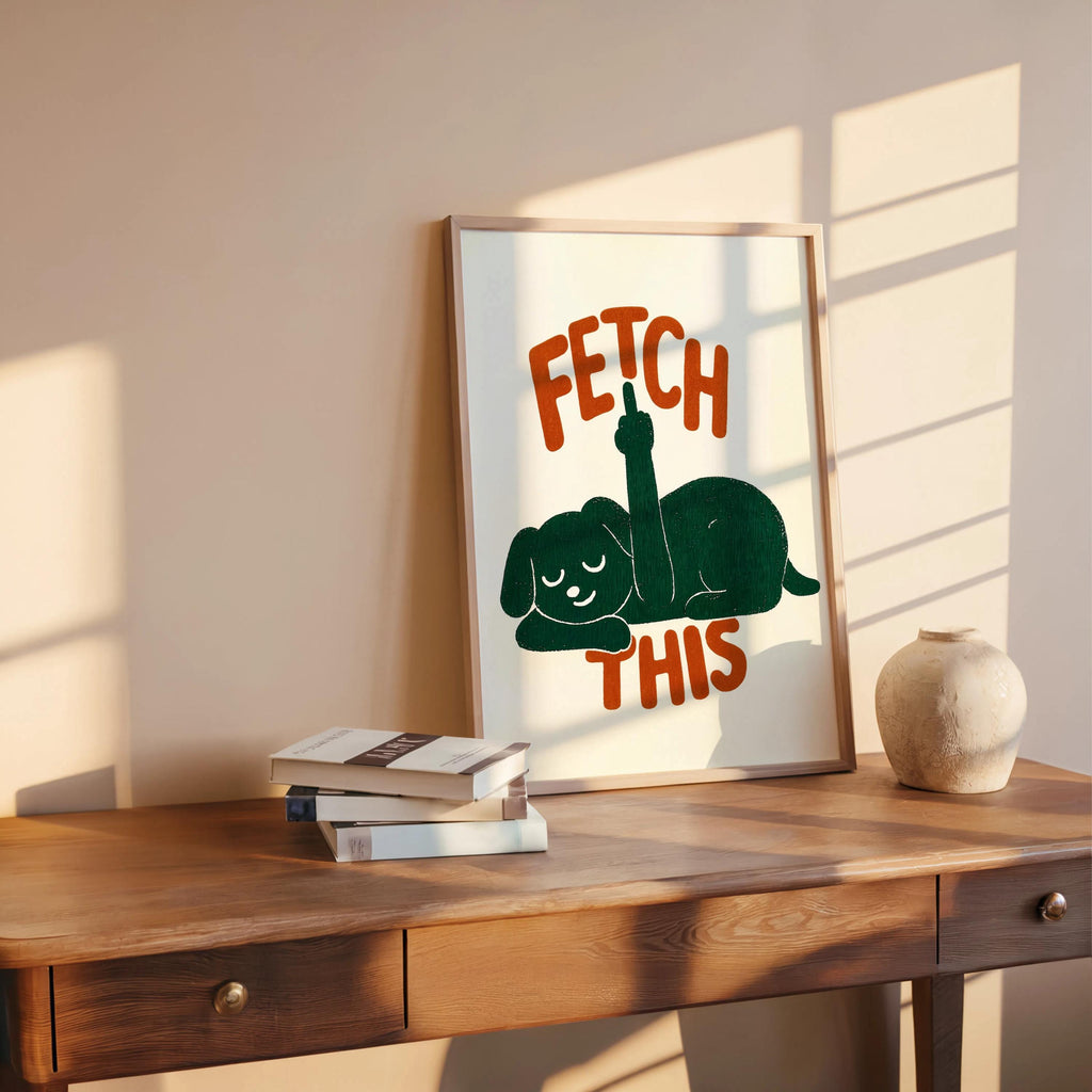 Wooden tabletop display with framed cream poster, forest green dog silhouette and orange retro FETCH THIS lettering, playful dog decor