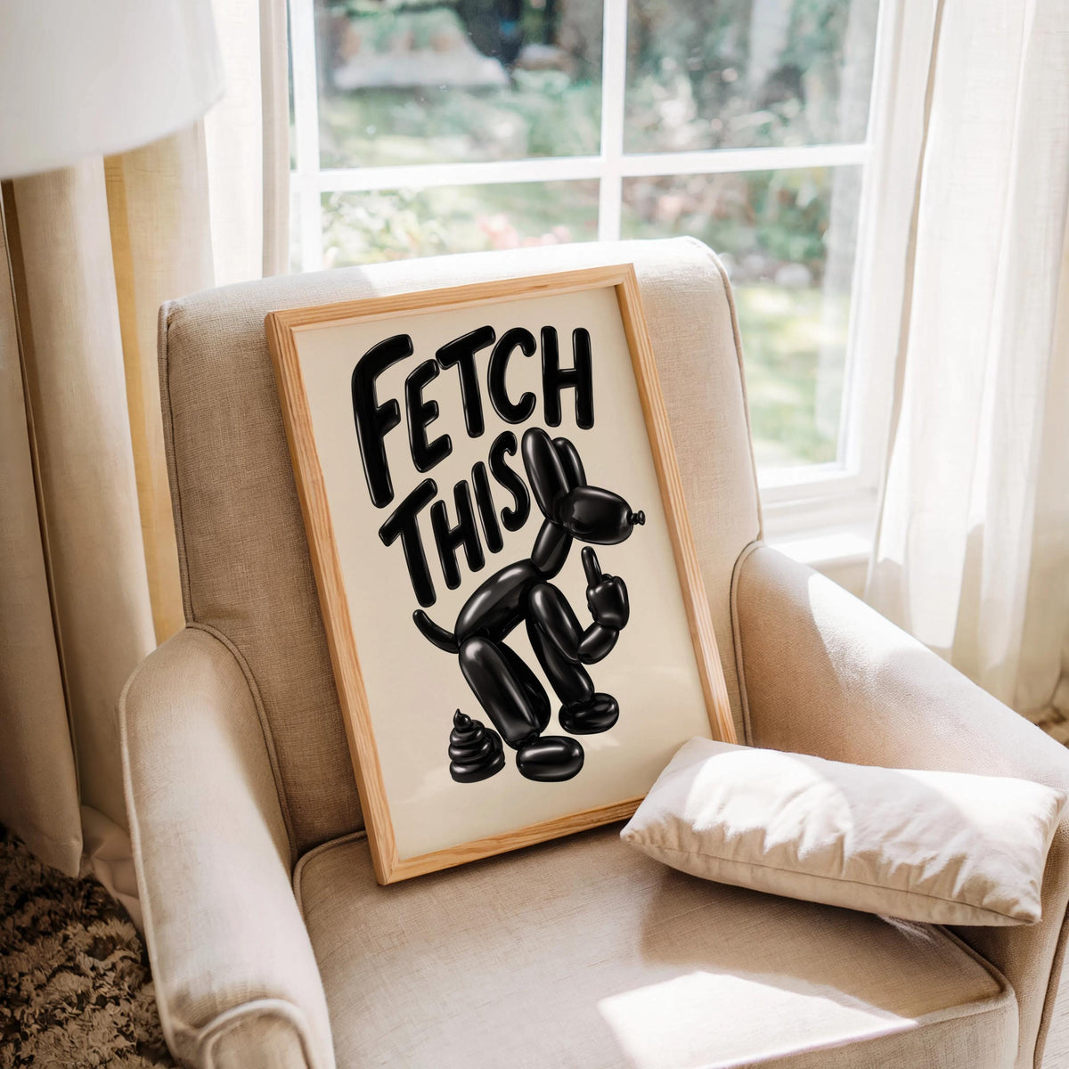 Leaning on an upholstered armchair by a window, bold FETCH THIS typography with glossy balloon dog, funny pet wall art