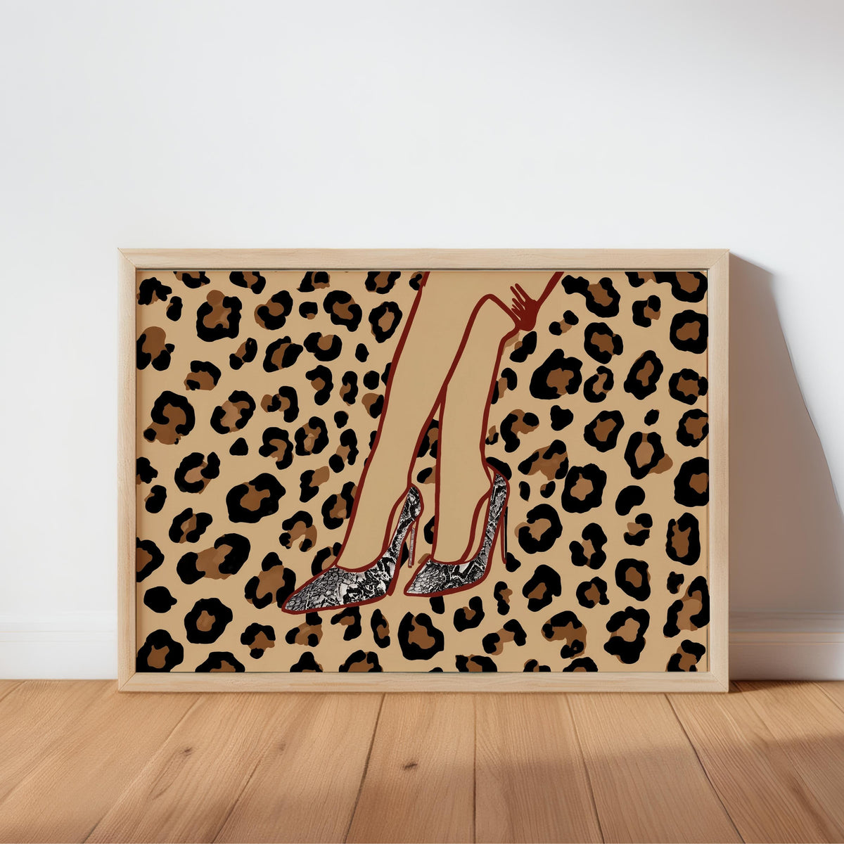 Framed leopard print high heel wall art leaning on warm wood floor, snake-skin stiletto detail