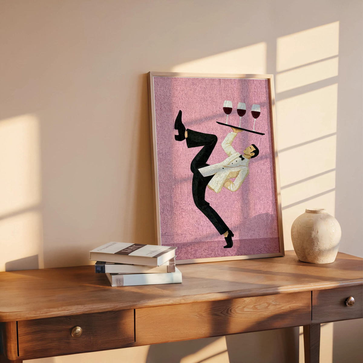 Pink print leaning on oak table beside books and a vase, silhouetted waiter with tray, wine bar wall art, cocktail kitchen wall art