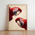Framed macaw parrot wall art print leaning on light wood floor, natural frame, two scarlet macaws peeking playfully
