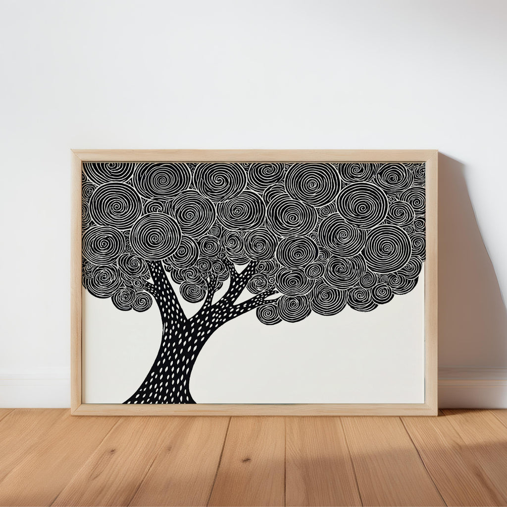 Framed black and white tree wall art leaning on a wooden table, bold linocut canopy detail